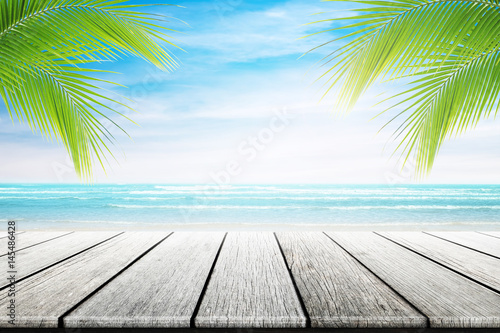 Fototapeta Naklejka Na Ścianę i Meble -  Empty wooden table and palm leafs with party on beach background blurred. Concept Summer, Beach, Sea, Relax, Party.