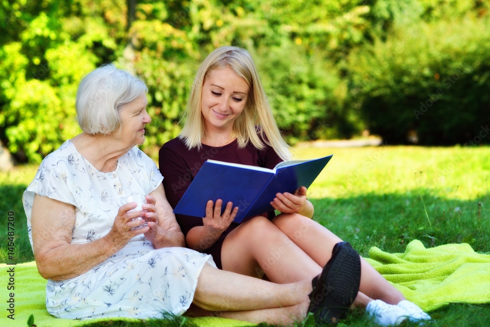 Young woman reading a book elderly woman in the park.