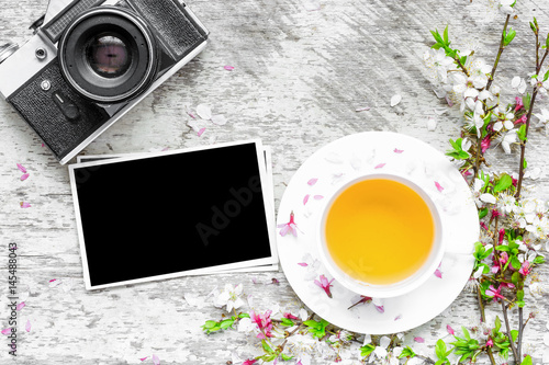 vintage retro camera, blank photo and cup of green tea with branches