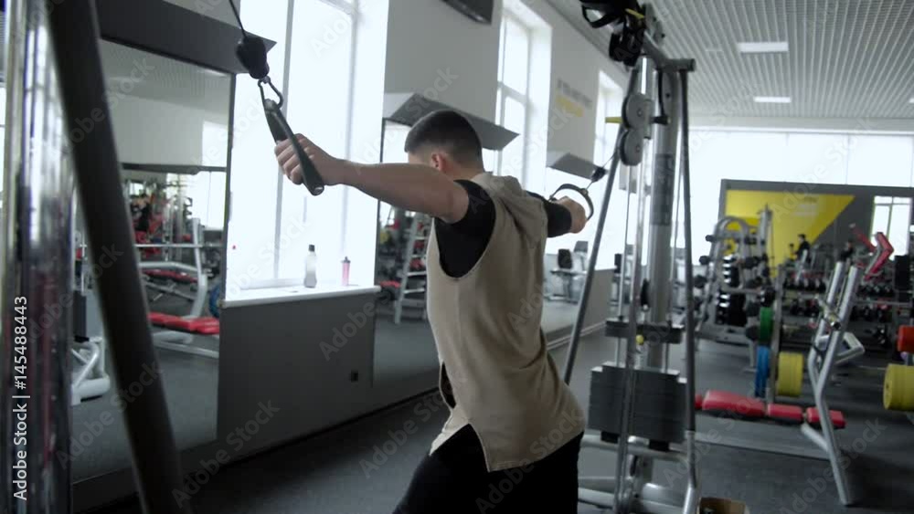 A young guy pumping his chest and biceps on the crossover, in the gym A young guy pumping his chest and biceps on the crossover, in the gym