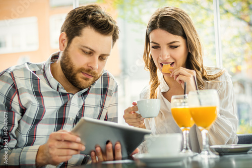 cheerful couple sitting in a cafe and using a digital tablet