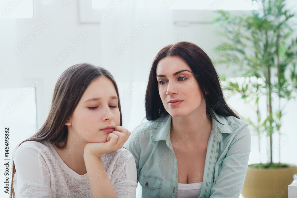 Caring loving mother cheering up her sad teenage daughter with teenage problems Caring loving mother cheering up her sad teenage daughter with teenage problems