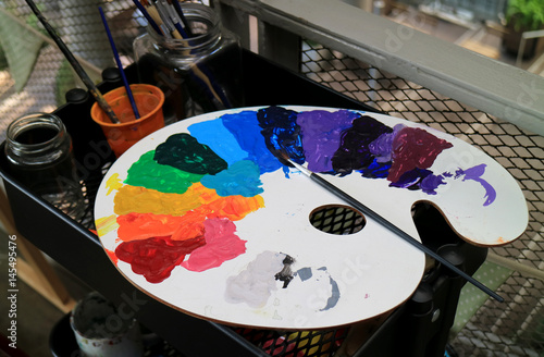 White art palette with multi-color paints and paintbrush on black tool cart