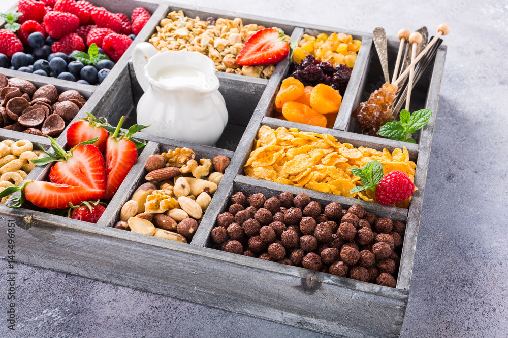 Old gray wooden box with variety of cold quick breakfast cereals and berries for breakfast, healthy eating concept, selective focus.