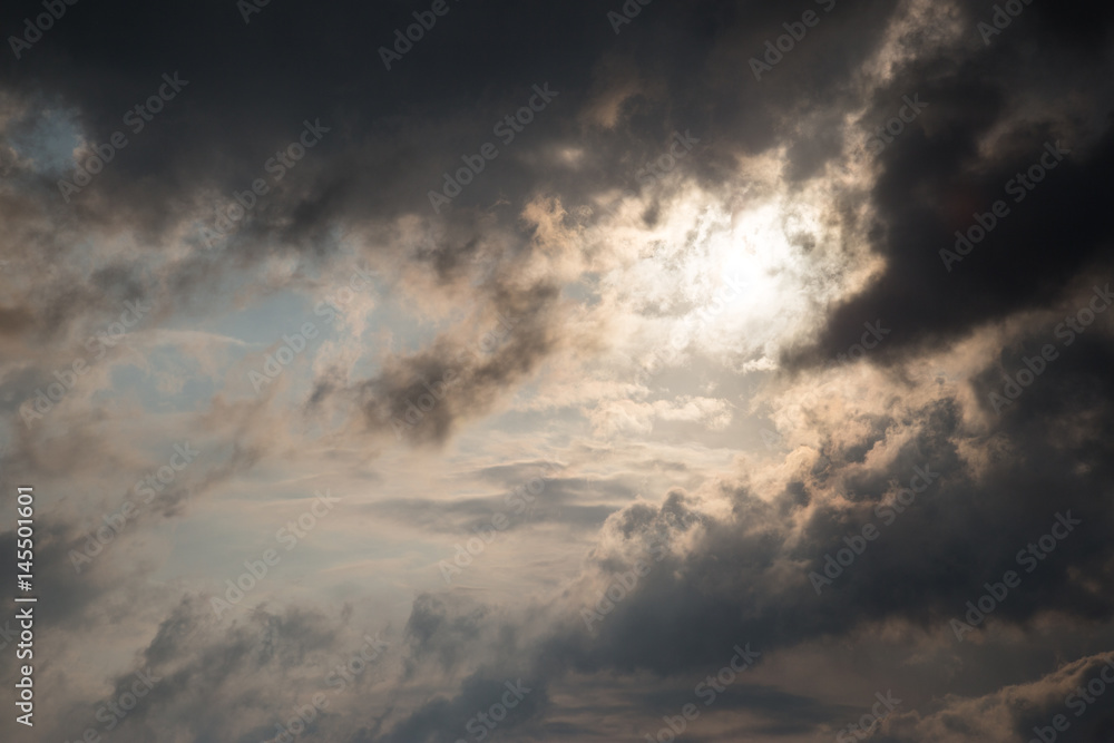 A close photo of some moody and dark clouds, with strong light coming out through a hole