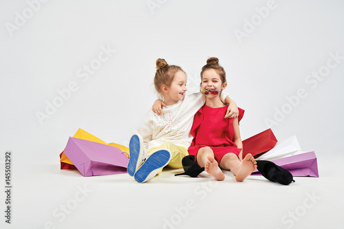 Obraz na plátně Laughing girls are sitting with shoppers bags