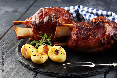 Photography Smoked ham hock with herbs and spices on wooden plate.