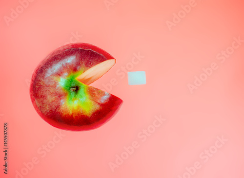 Foto Creative idea with apple like character computer game pacman on red pastel background