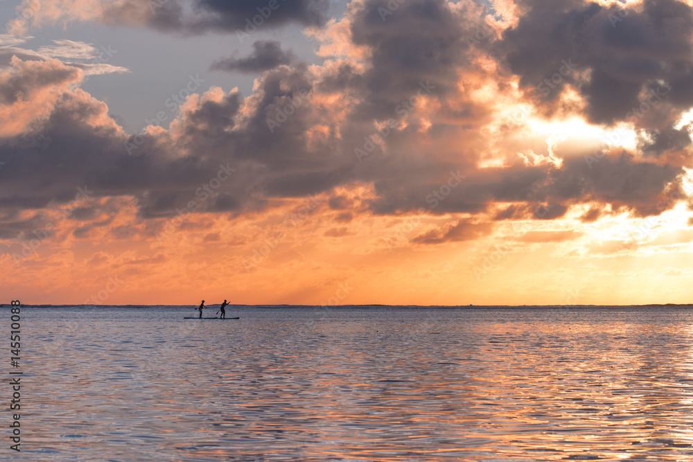 People paddleboarding at sunrise