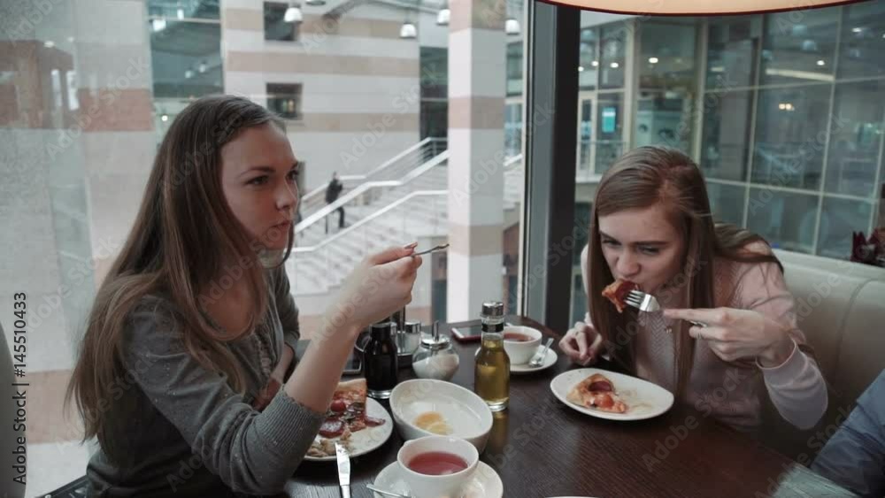 Friends Two young women met at a cafe, business lunch. Talk and eat Italian pizza