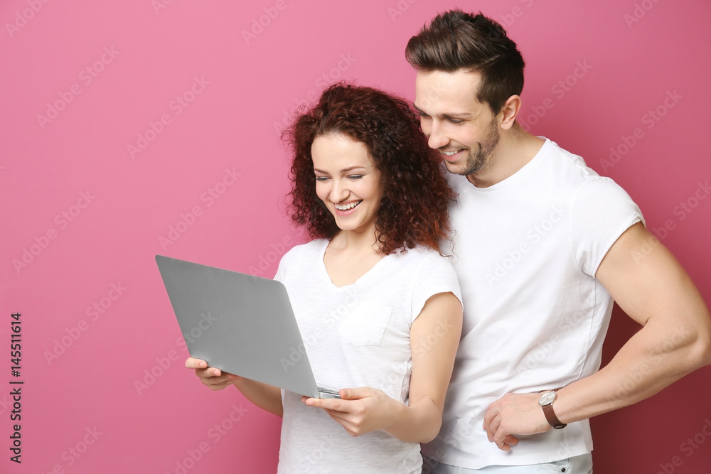Happy young couple with laptop on color background Happy young couple with laptop on color background