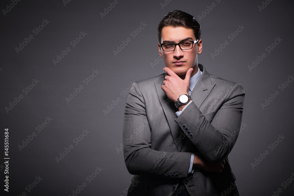 Handsome businessman against dark background Handsome businessman against dark background