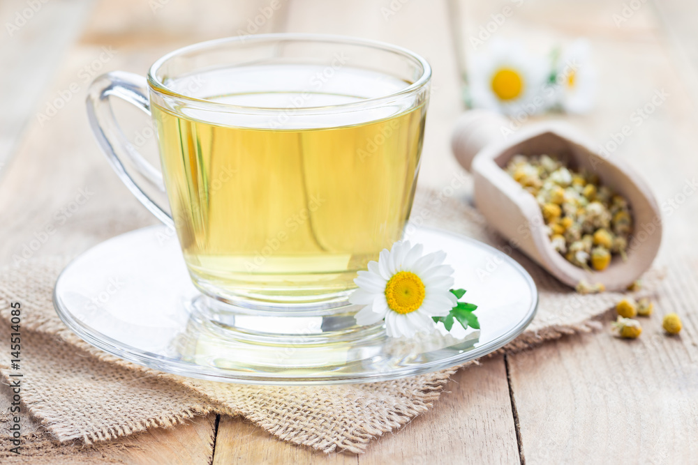 Chamomile tea in glass cup, chamomile flowers and dry tea on background, horizontal Chamomile tea in glass cup, chamomile flowers and dry tea on background, horizontal