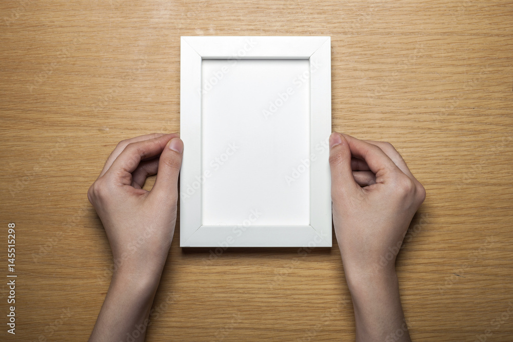 woman hand hold a photo frame on the wood table(background) woman hand hold a photo frame on the wood table(background)