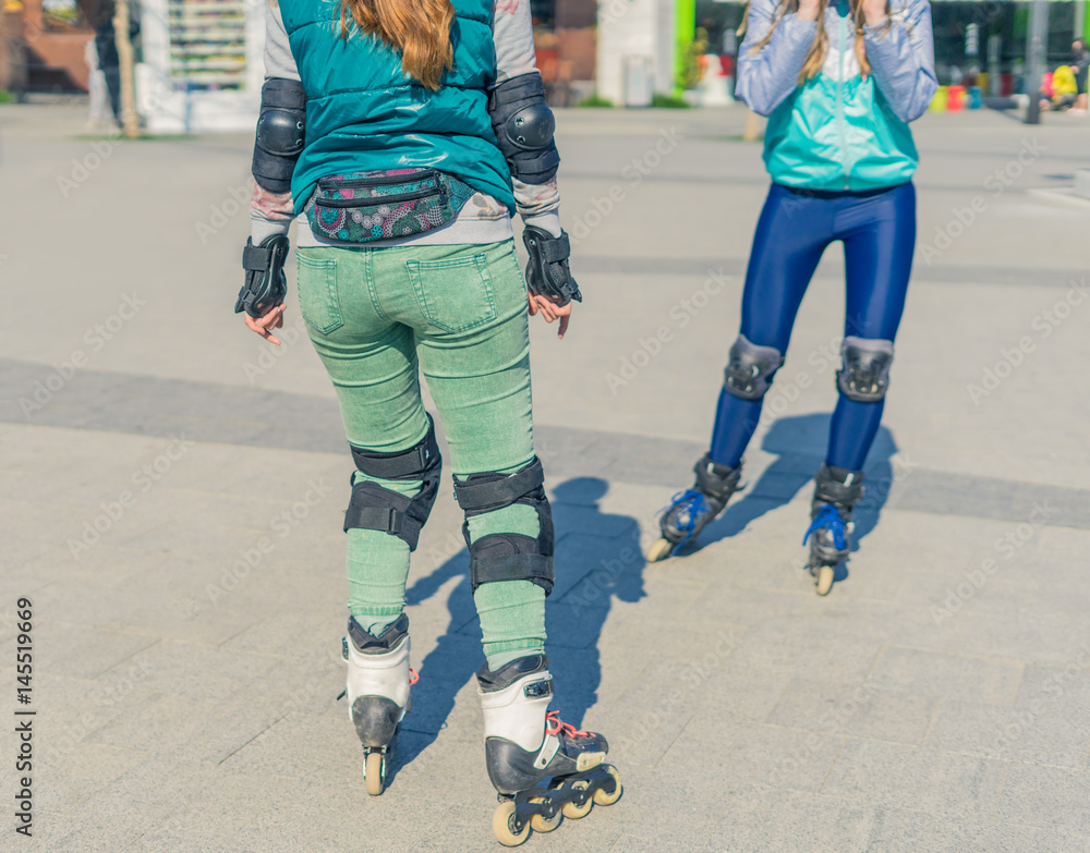 Two girls rollers meet each other in the park. Meeting of friends for roller skating. Two girls rollers meet each other in the park. Meeting of friends for roller skating.