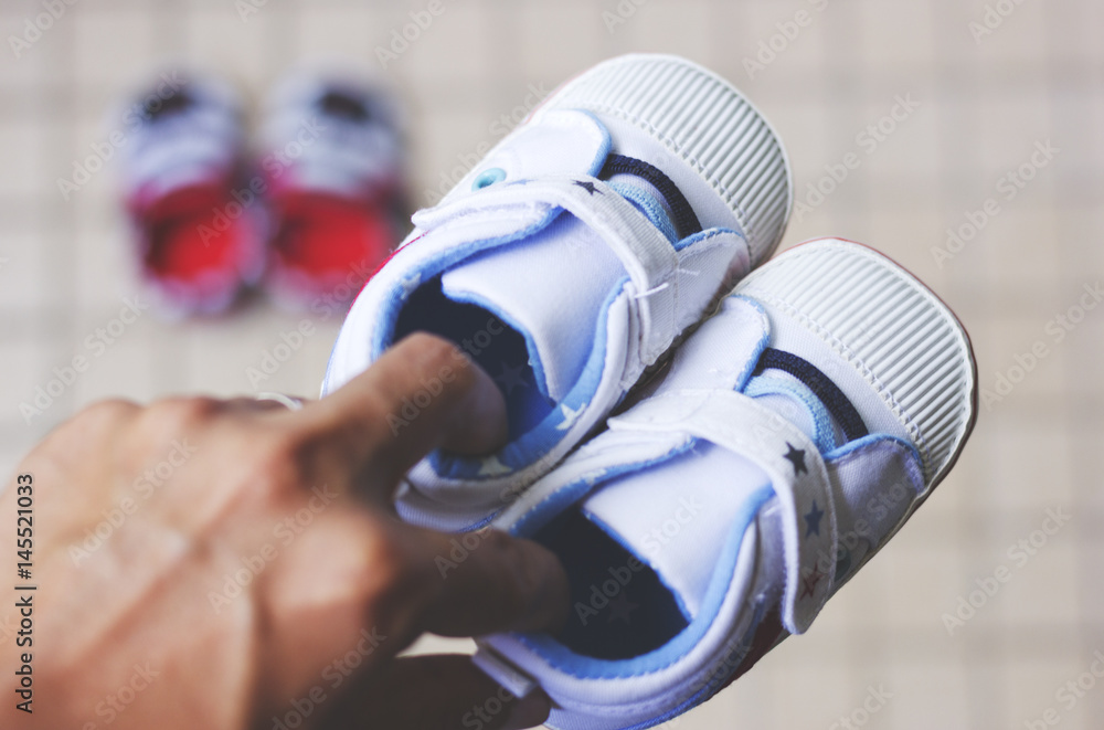 Fototapeta premium A father holding a pair of shoe for his newborn baby.