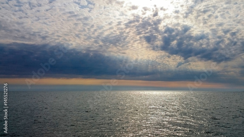 sun in sea with clouds in sky