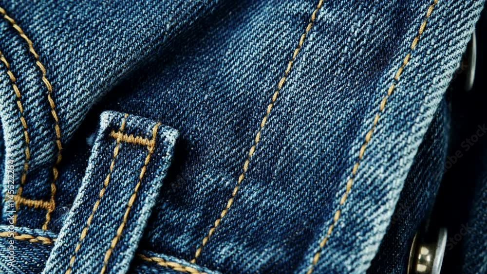 Closeup detail of blue denim jeans front view button zip, belt loop and pocket, texture background. Dolly sliding shot 4K ProRes HQ codec Closeup detail of blue denim jeans front view button zip, belt loop and pocket, texture background. Dolly sliding shot 4K ProRes HQ codec