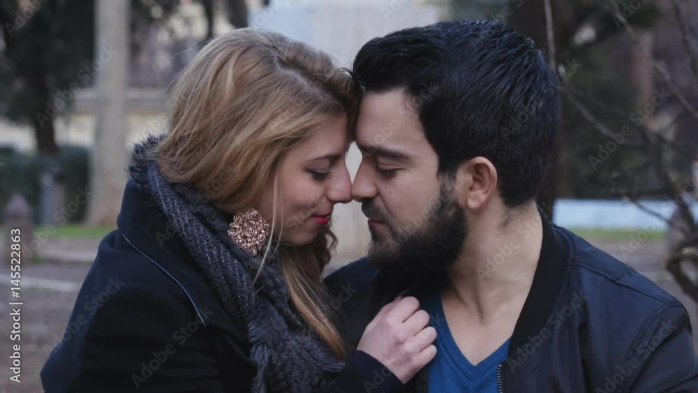 Loving couple at the park kisses tenderly,close up Loving couple at the park kisses tenderly,close up