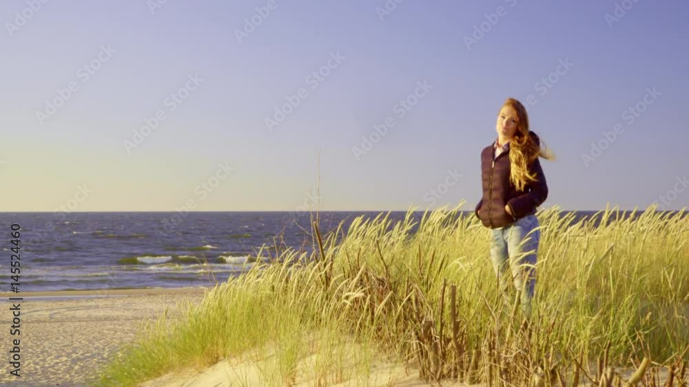 Girl spending free time on seashore. Young long hair woman walking on sandy beach dunes in summer cold windy day 4K ProRes HQ codec Girl spending free time on seashore. Young long hair woman walking on sandy beach dunes in summer cold windy day 4K ProRes HQ codec