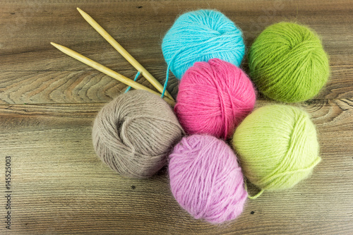 Colored wool balls with needles on a rustic wooden table