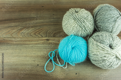 Colored wool balls with needles on a rustic wooden table