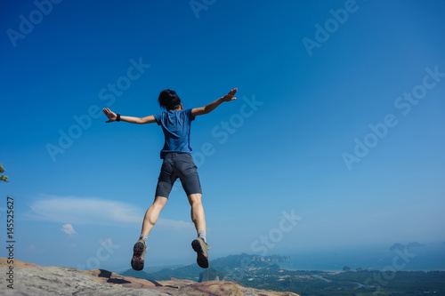 jumping on rocky mountain peak, freedom, risk, challenge, success concept