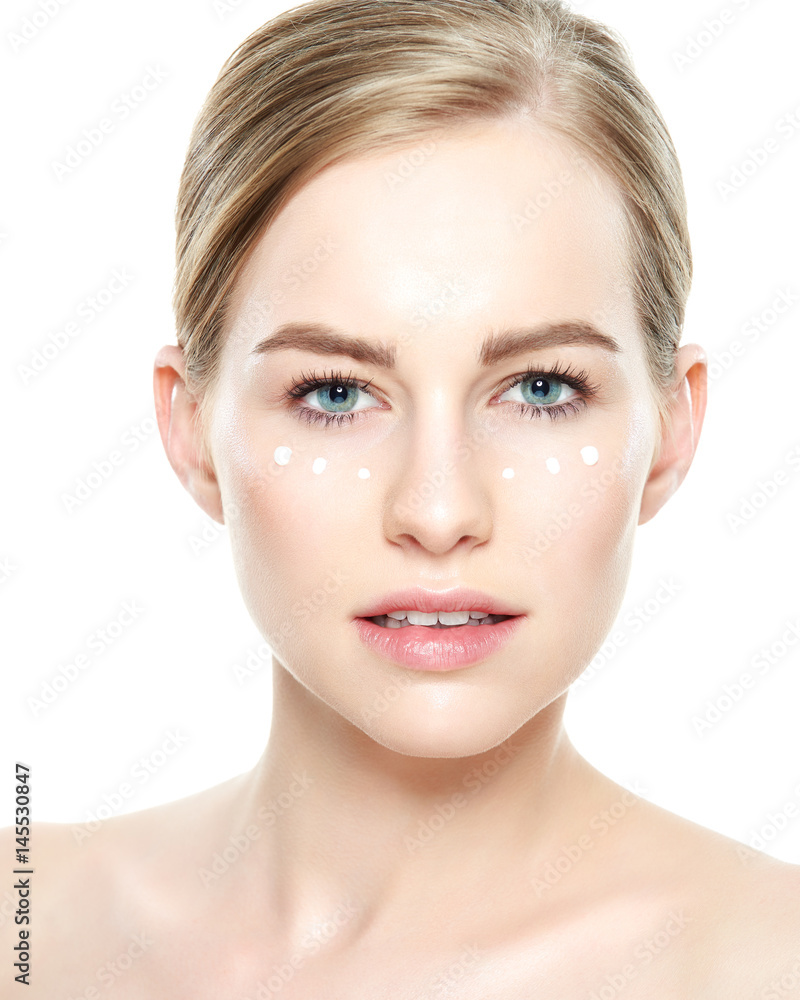 Beautiful Young Blond Woman with Face cream applied under her eyes. Facial treatment. Cosmetology, beauty and spa concept. Isolated on white background. Beautiful Young Blond Woman with Face cream applied under her eyes. Facial treatment. Cosmetology, beauty and spa concept. Isolated on white background.