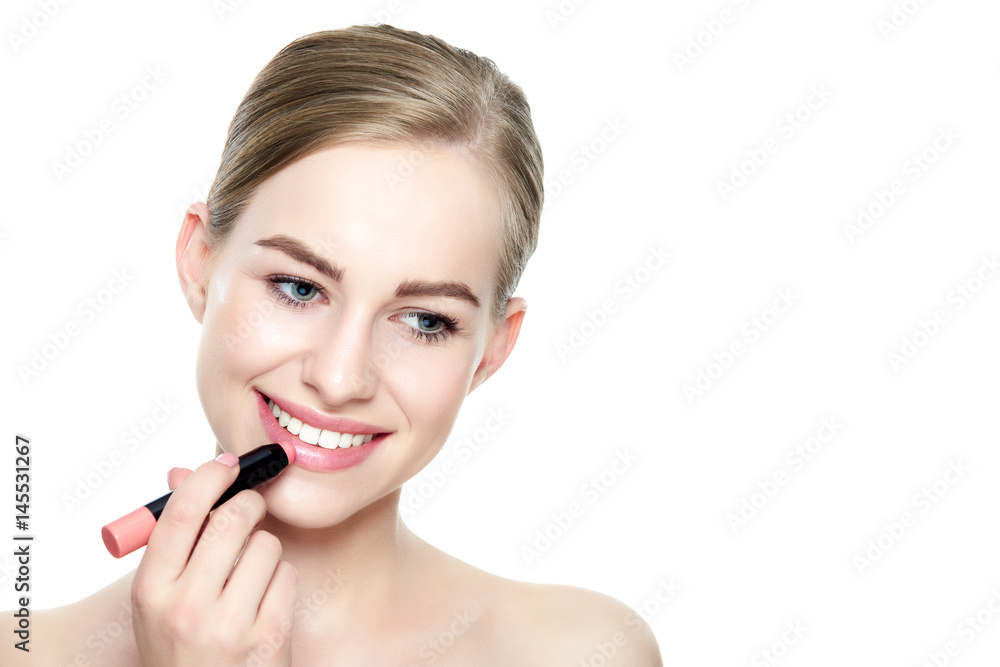 Beautiful young blond woman with sexy full lips applying coral color lipstick. Beauty portrait isolated over white background with copy space. Beautiful young blond woman with sexy full lips applying coral color lipstick. Beauty portrait isolated over white background with copy space.