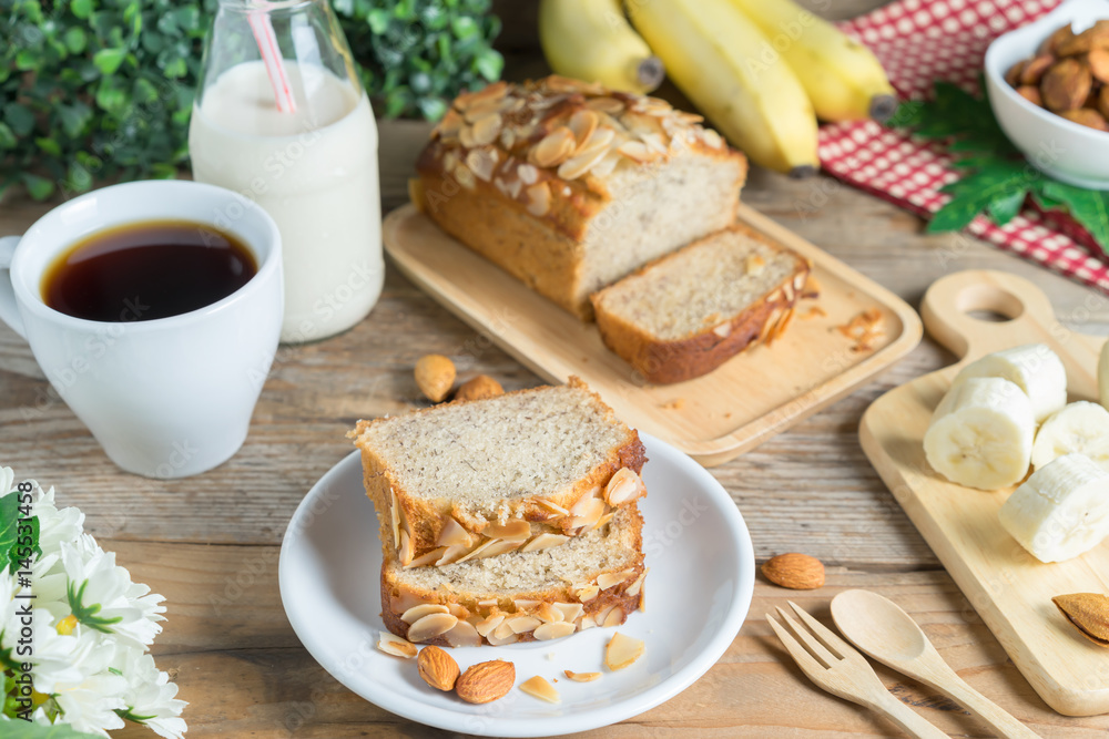 Slice of Banana cake topping with almond slice and banana, coffee, milk. Slice of Banana cake topping with almond slice and banana, coffee, milk.