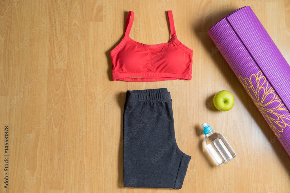 Set for yoga practice women's sport wear with yoga mat, bottle of water and green apple. Top view. Set for yoga practice women's sport wear with yoga mat, bottle of water and green apple. Top view.