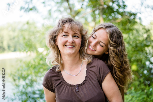 Pretty cheerful teen girl hugging her mother with love
