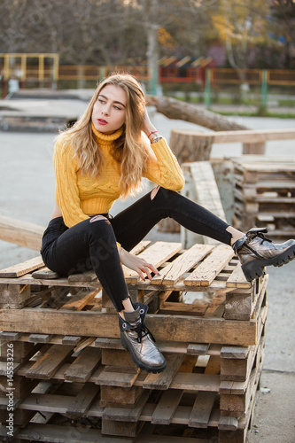 Portrait. A beautiful sexy girl, blond, a young woman looking like Jennifer Aniston is sitting in ruins, wooden pallets. Red lips. photo