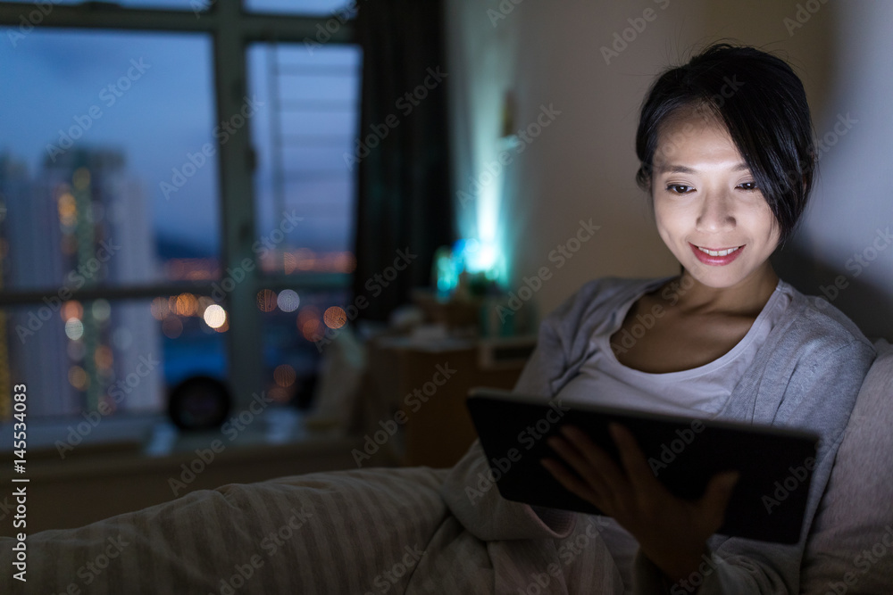Woman using digital tablet in home at night Woman using digital tablet in home at night