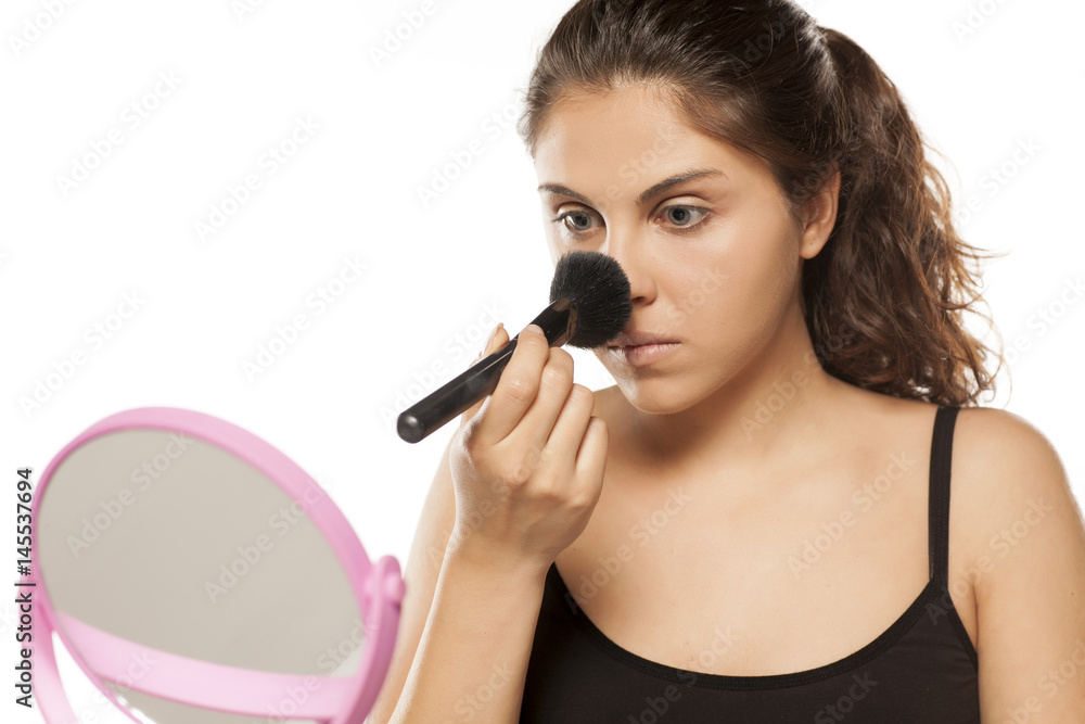 young beautiful woman applied powder on her nose young beautiful woman applied powder on her nose