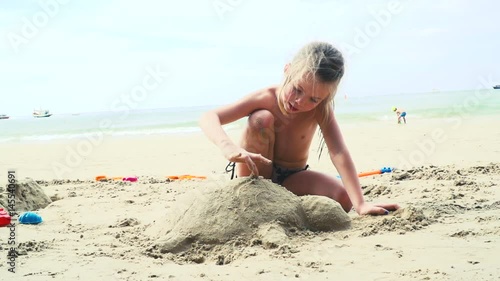 blondes mädchen spielt mit sand auf einem strand in thailand