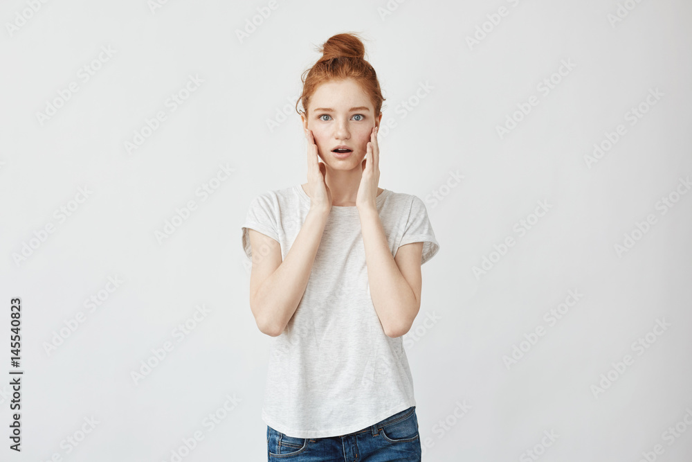 Portrait of redhead surprised girl with hands on cheeks. White background, copy space. Portrait of redhead surprised girl with hands on cheeks. White background, copy space.