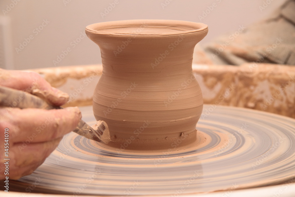 Hands of a potter, creating an earthen jar on pottery wheel. Hands of a potter, creating an earthen jar on pottery wheel.