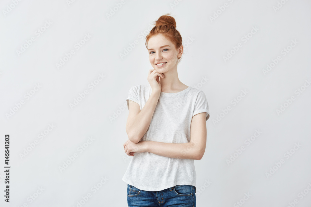 Portrait of young beautiful redhead girl with freckled skin smiling looking at camera. Copy space. Isolated on white background. Portrait of young beautiful redhead girl with freckled skin smiling looking at camera. Copy space. Isolated on white background.
