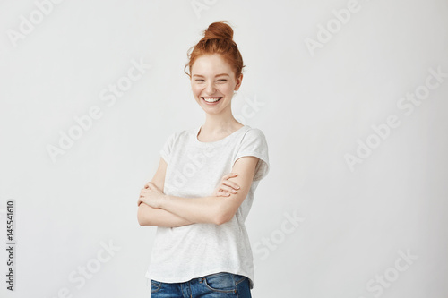Portrait of happy young beautiful ginger girl laughing. Off camera. Copy space. Isolated on white. photo