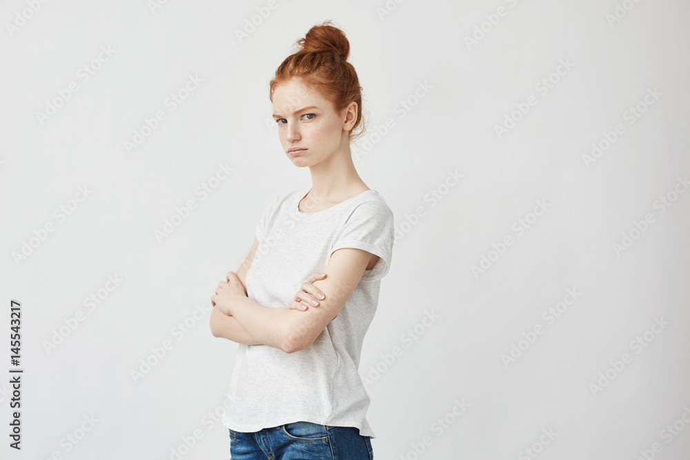 Portrait of redhead displeased girl with crossed arms. Copy space. Isolated on white . Portrait of redhead displeased girl with crossed arms. Copy space. Isolated on white .