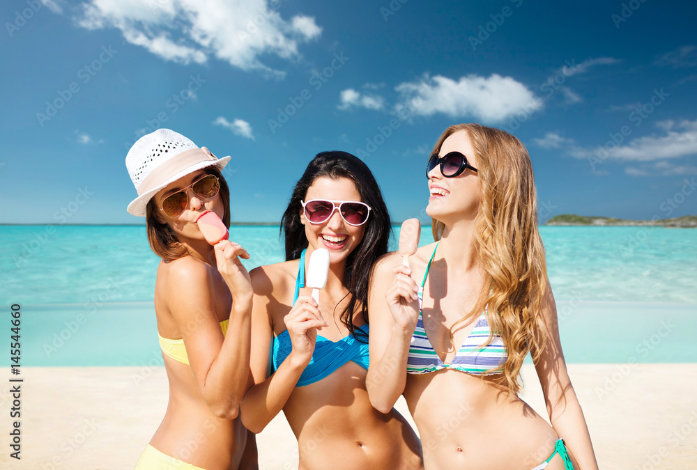 group of smiling women eating ice cream on beach
