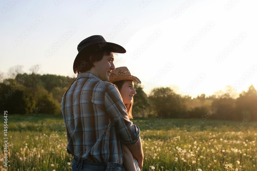 couple of young people walking in the sunset spring evening in a field couple of young people walking in the sunset spring evening in a field