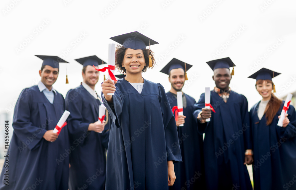 happy students in mortar boards with diplomas happy students in mortar boards with diplomas