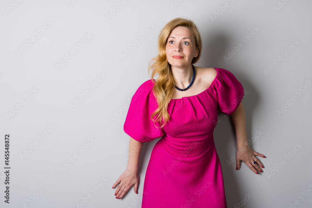 Beautiful woman in a pink dress near a wall Beautiful woman in a pink dress near a wall