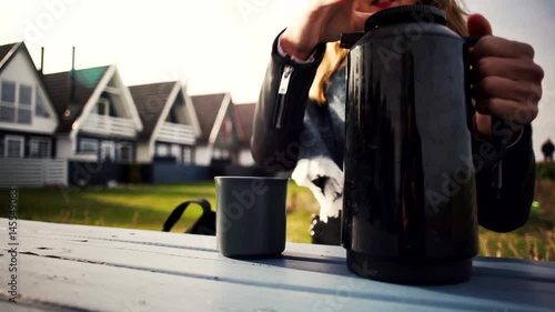 the girl pours coffee from a thermos flask outdoors