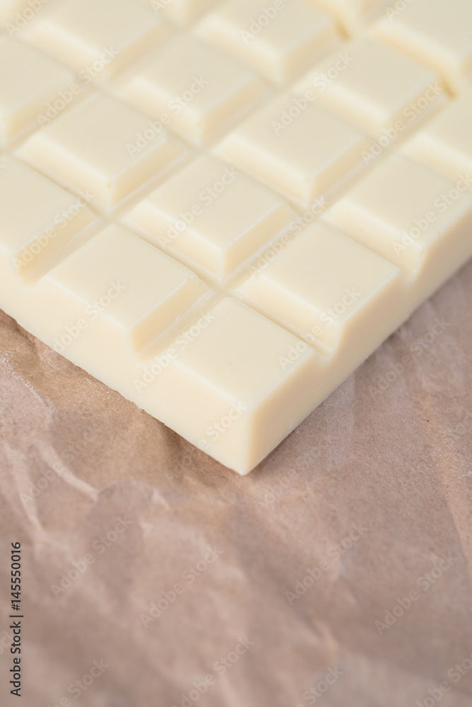 Close-up of white chocolate bar over paper