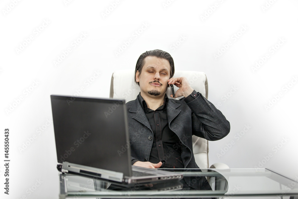 A businessman is talking on his cell phone and working in his office. A businessman is talking on his cell phone and working in his office.