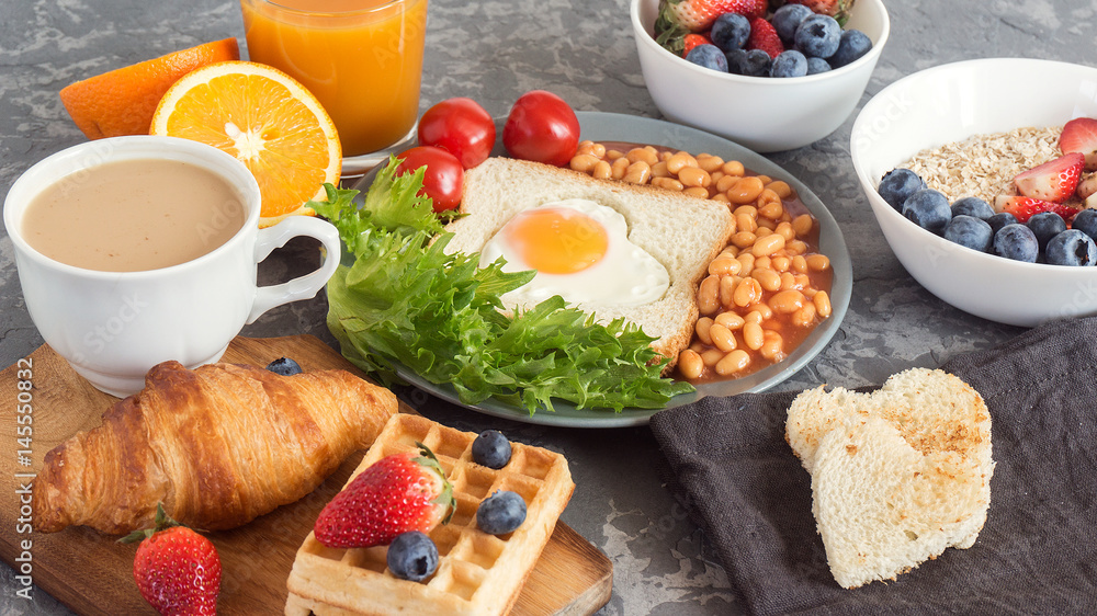 Full English Breakfast with fried eggs, beans, toasts, salad, tomatoes on gray background