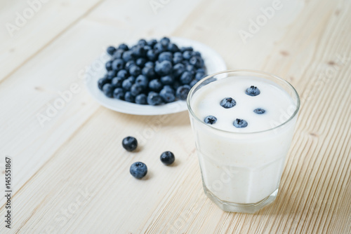 Rustic healthy breakfast with blueberry and yogurt in a glass on a wooden table. Glass of homemade yogurt with ripe berries. Healthy breakfast with vital vitamins.